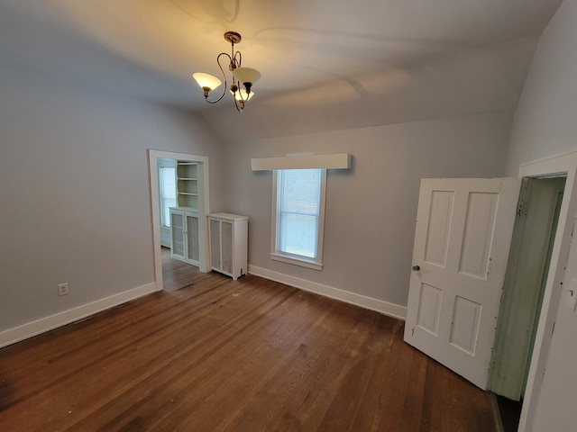 spare room with lofted ceiling, dark hardwood / wood-style floors, and a chandelier