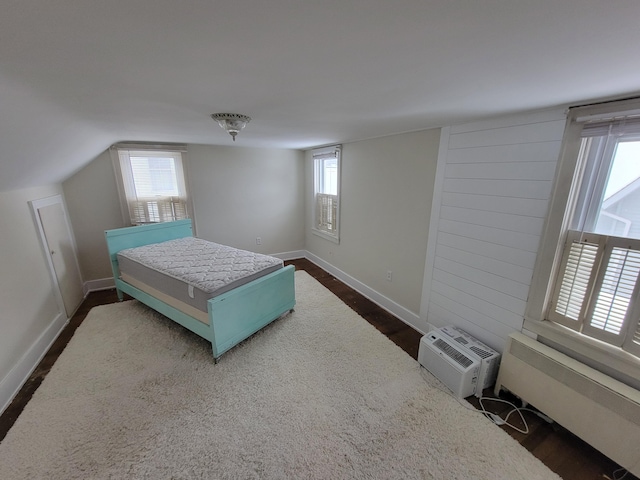 bedroom with lofted ceiling, dark hardwood / wood-style floors, and a wall mounted AC