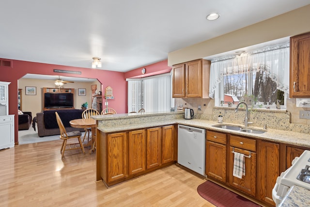 kitchen with sink, dishwashing machine, kitchen peninsula, decorative backsplash, and white range oven