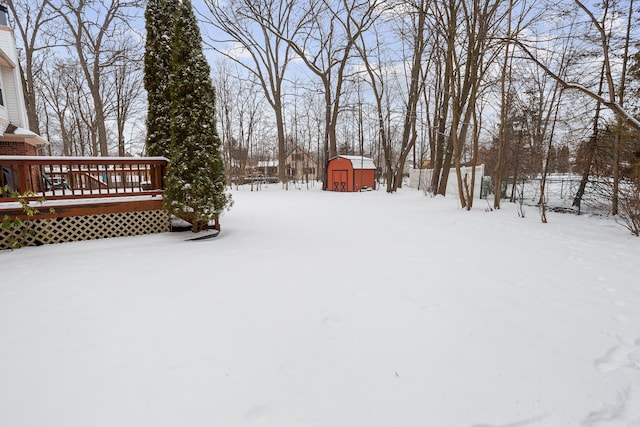 yard covered in snow featuring a shed and a deck