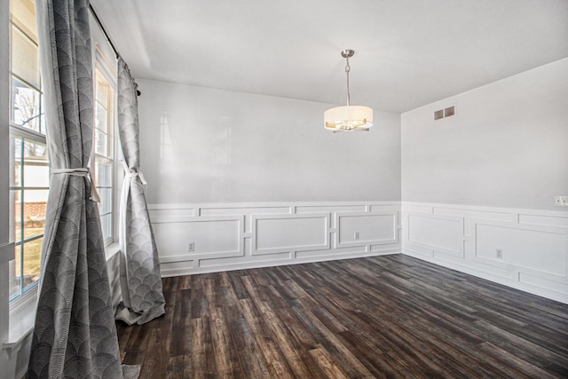 empty room featuring dark hardwood / wood-style floors and a notable chandelier