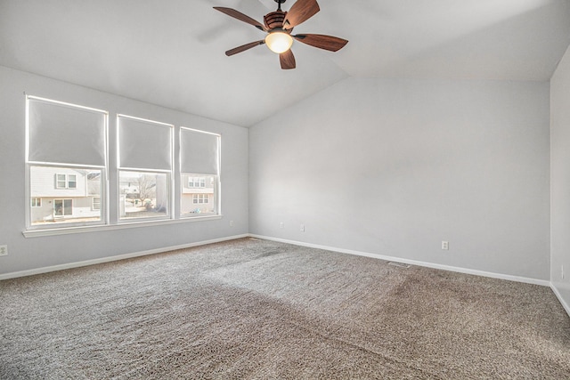 carpeted spare room featuring vaulted ceiling and ceiling fan