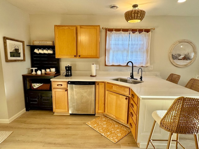 kitchen featuring light hardwood / wood-style flooring, sink, a breakfast bar, stainless steel dishwasher, and kitchen peninsula