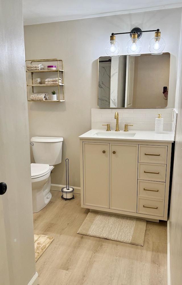 bathroom featuring backsplash, hardwood / wood-style flooring, toilet, and vanity