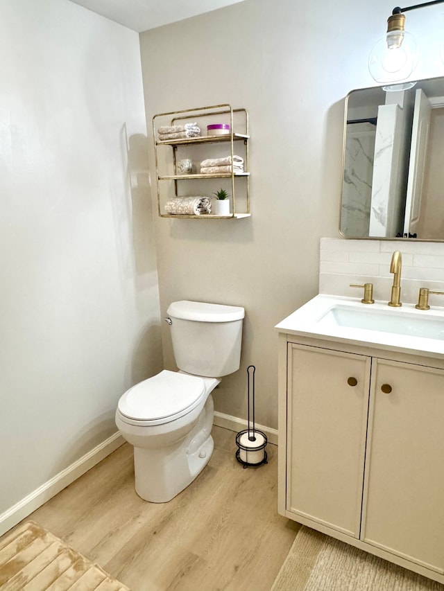 bathroom with hardwood / wood-style flooring, vanity, backsplash, and toilet