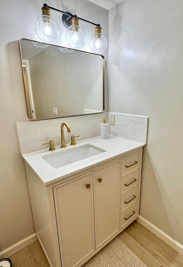 bathroom featuring hardwood / wood-style flooring, decorative backsplash, and vanity