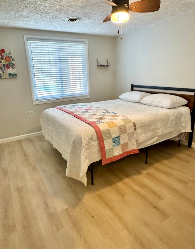 bedroom with hardwood / wood-style flooring, ceiling fan, and a textured ceiling