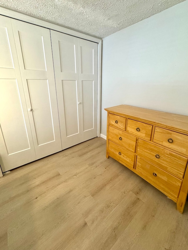 bedroom with a textured ceiling, a closet, and light hardwood / wood-style floors