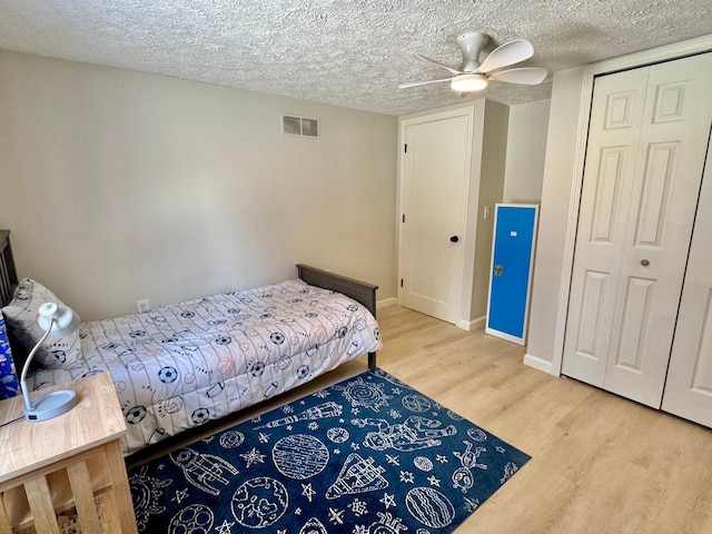 bedroom with ceiling fan, a closet, wood-type flooring, and a textured ceiling