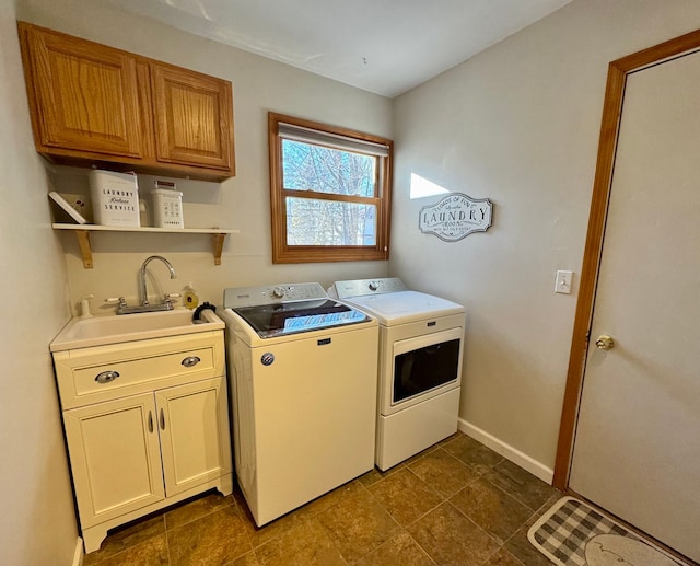 clothes washing area featuring cabinets, sink, and separate washer and dryer