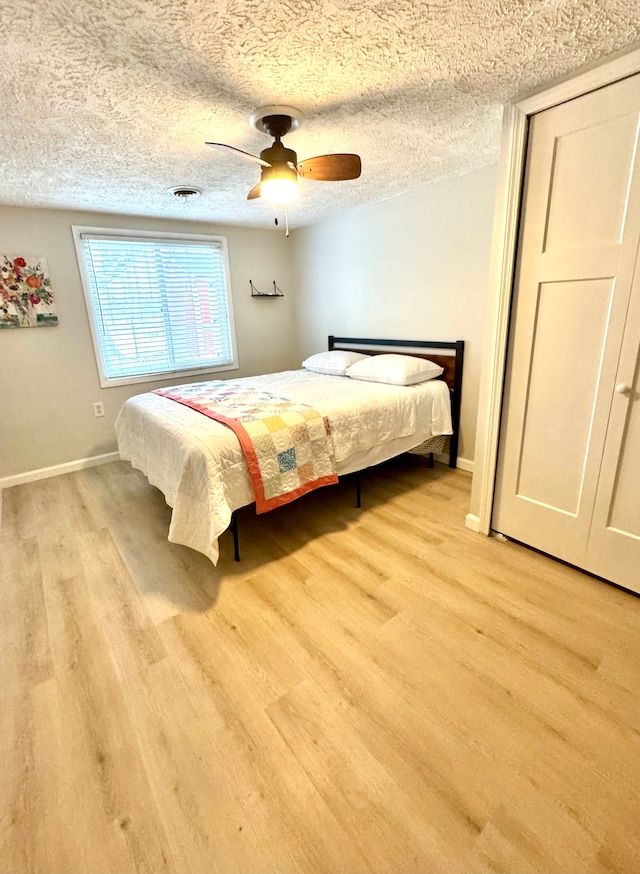 bedroom featuring ceiling fan, light hardwood / wood-style floors, and a textured ceiling