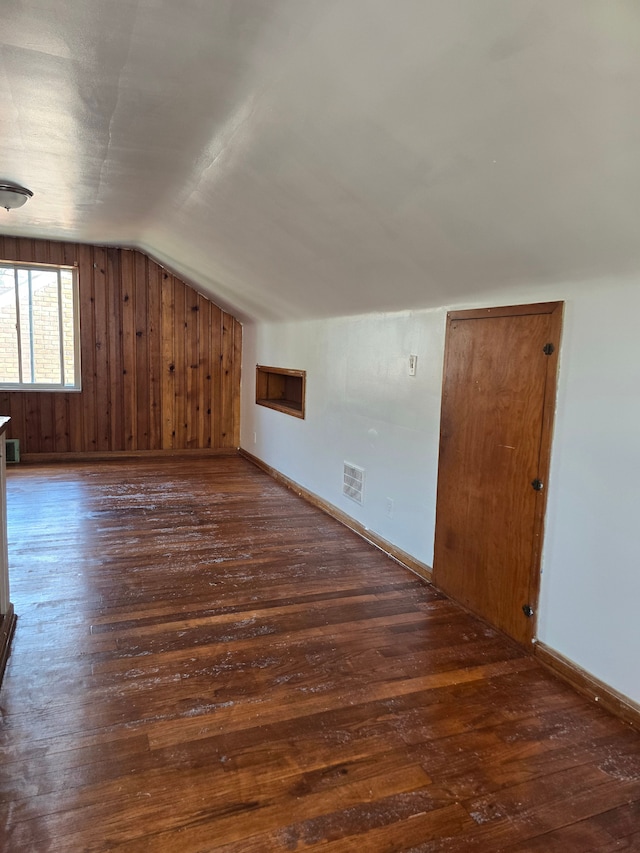 bonus room with lofted ceiling, dark hardwood / wood-style flooring, and wood walls