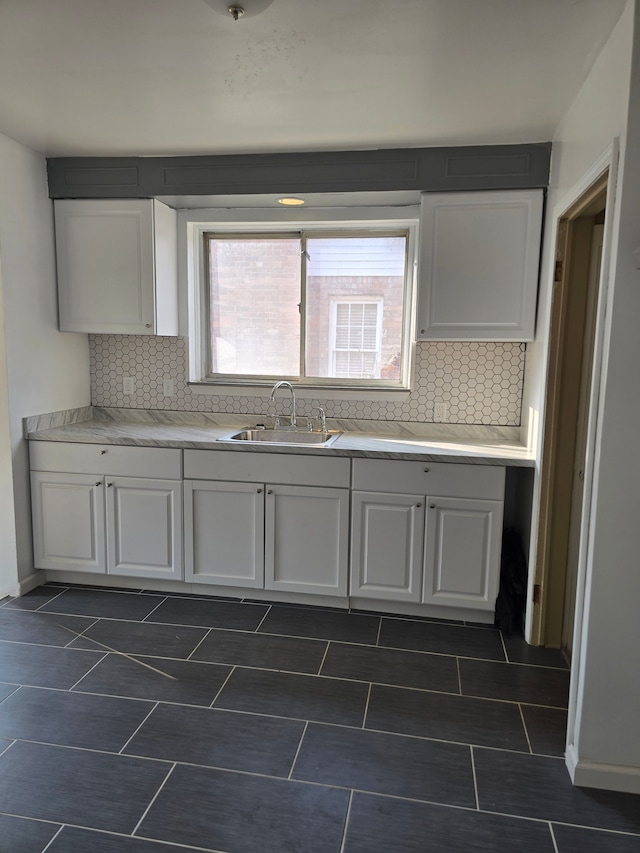 kitchen featuring tasteful backsplash, sink, and white cabinets