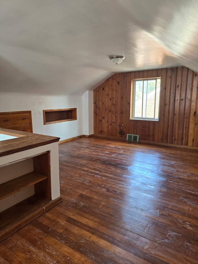 bonus room featuring dark wood-type flooring, lofted ceiling, and wood walls