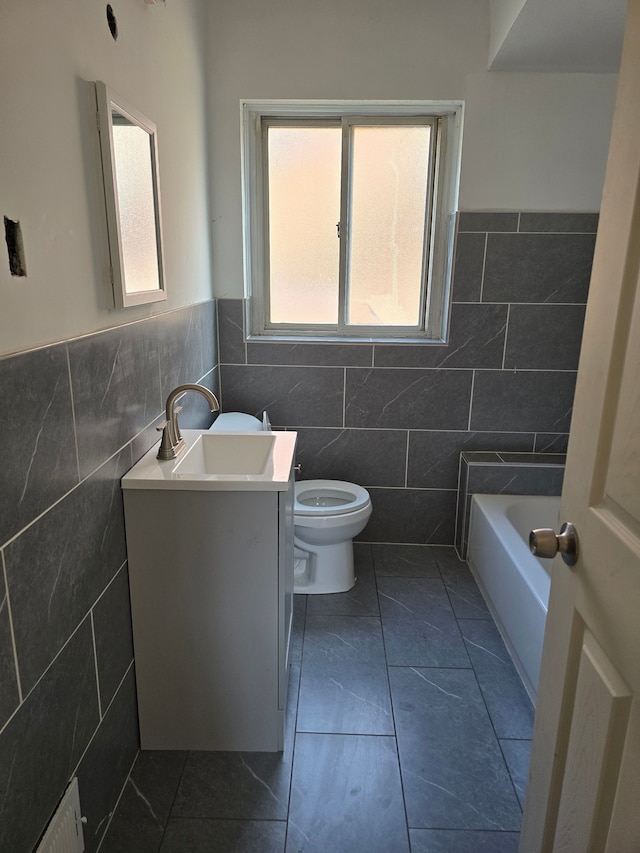 bathroom with vanity, a tub, tile walls, and toilet