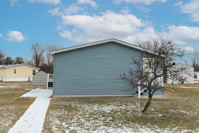 snow covered property with a yard and a storage shed