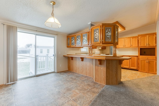 kitchen with hanging light fixtures, a breakfast bar area, a textured ceiling, and kitchen peninsula