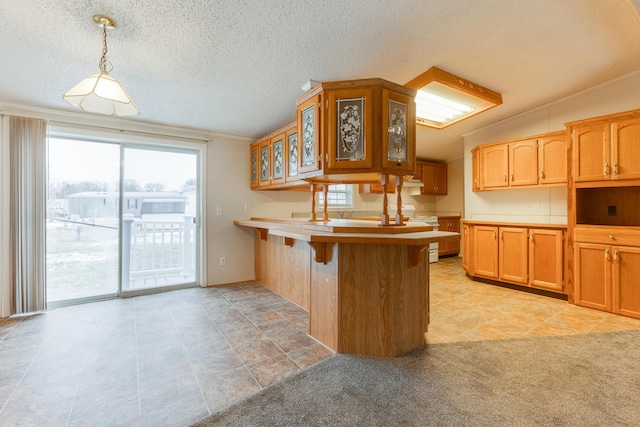 kitchen featuring a breakfast bar area, kitchen peninsula, a textured ceiling, and decorative light fixtures