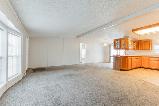 unfurnished living room featuring light carpet, a wealth of natural light, lofted ceiling with beams, and a textured ceiling