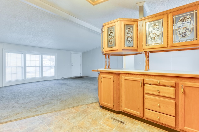 kitchen featuring light carpet, vaulted ceiling with beams, and a textured ceiling