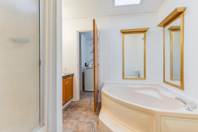 full bathroom with toilet, washer / dryer, separate shower and tub, a textured ceiling, and vanity