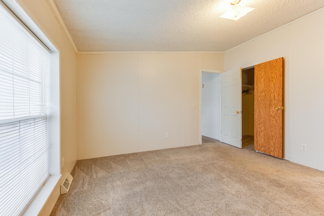 carpeted spare room with ornamental molding and a textured ceiling