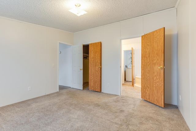 unfurnished bedroom featuring washer / dryer, light carpet, a textured ceiling, and a closet