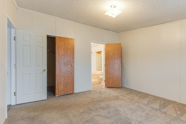 unfurnished bedroom with light colored carpet, connected bathroom, and a textured ceiling