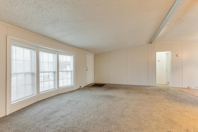 spare room featuring vaulted ceiling with beams, a textured ceiling, and carpet flooring