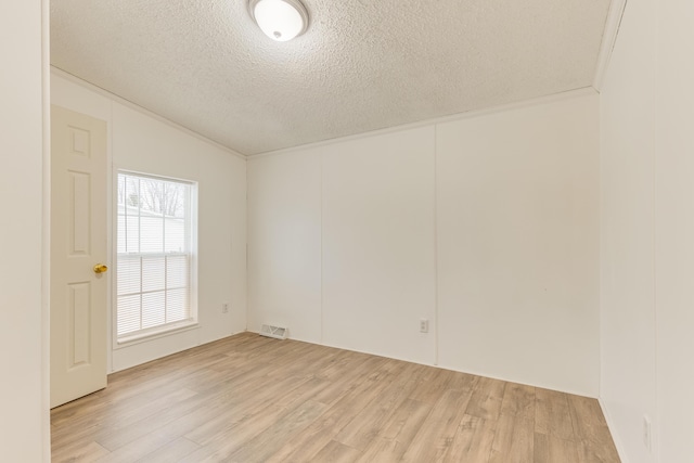 empty room featuring vaulted ceiling, a textured ceiling, and light hardwood / wood-style floors