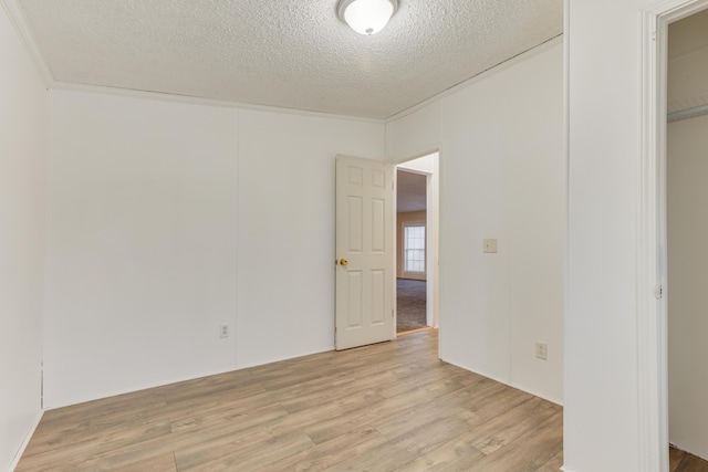 spare room featuring light hardwood / wood-style floors and a textured ceiling