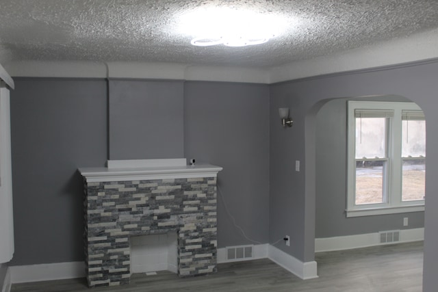 unfurnished living room featuring a tile fireplace, hardwood / wood-style floors, and a textured ceiling