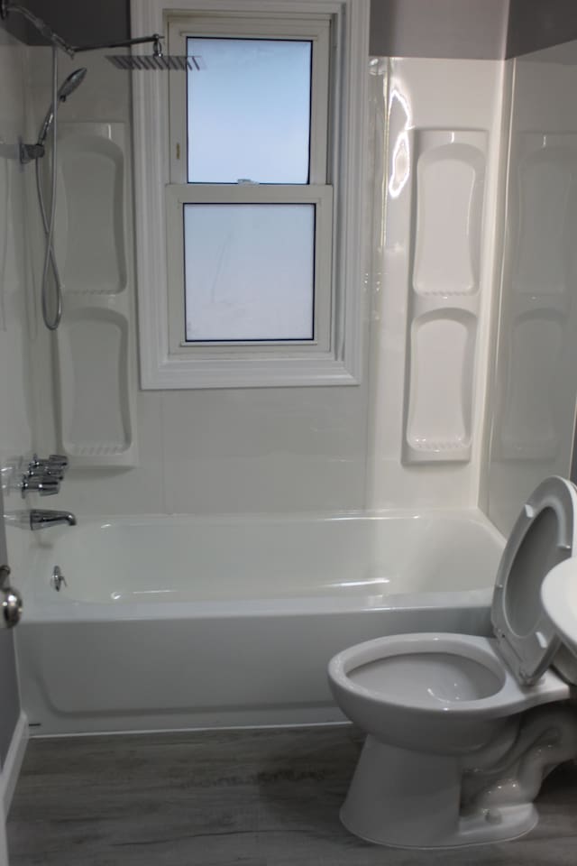 bathroom featuring hardwood / wood-style flooring, shower / washtub combination, and toilet