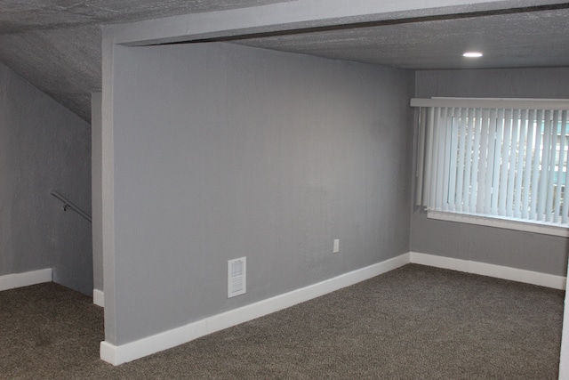 empty room featuring a textured ceiling and dark colored carpet