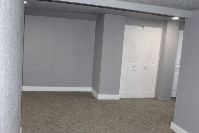 basement featuring dark carpet and a textured ceiling