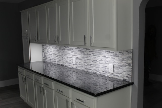 kitchen featuring backsplash, dark stone countertops, and white cabinets