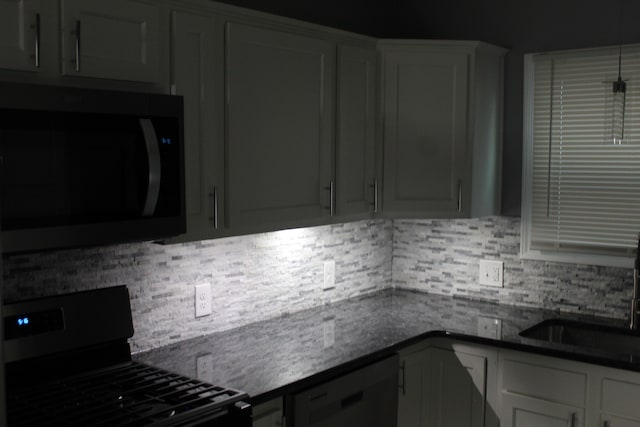 kitchen with tasteful backsplash, sink, dark stone countertops, and black appliances