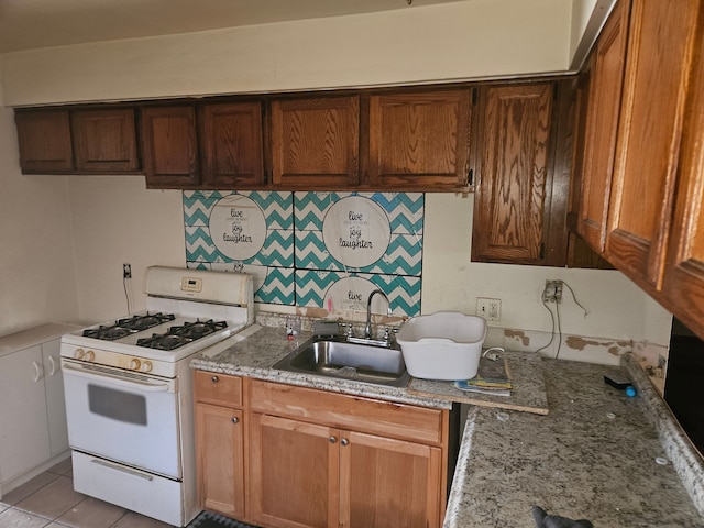 kitchen with light tile patterned floors, sink, tasteful backsplash, light stone countertops, and white gas range