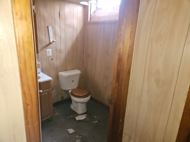 bathroom with wooden walls, vanity, and toilet