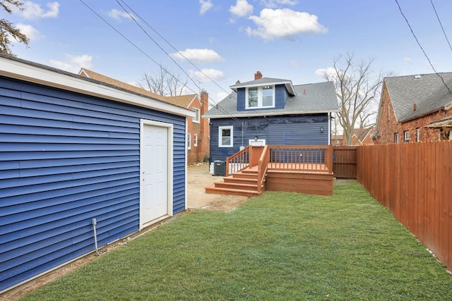 rear view of house featuring a wooden deck, a yard, and an outdoor structure