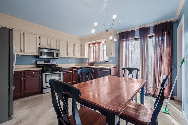 kitchen featuring appliances with stainless steel finishes, sink, a chandelier, light tile patterned floors, and crown molding