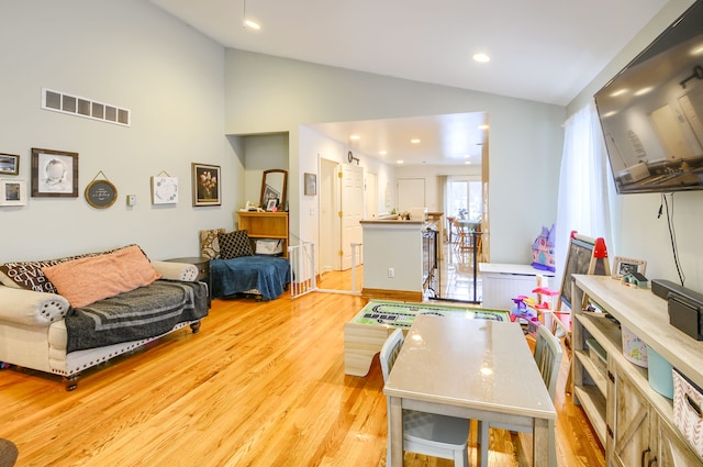 living room featuring high vaulted ceiling and light hardwood / wood-style floors