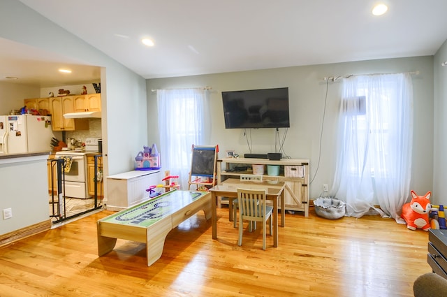 living room with vaulted ceiling, plenty of natural light, and light hardwood / wood-style floors