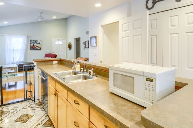 kitchen with lofted ceiling, sink, light tile patterned floors, light brown cabinets, and dishwasher