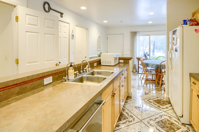 kitchen featuring white appliances, light brown cabinetry, and sink