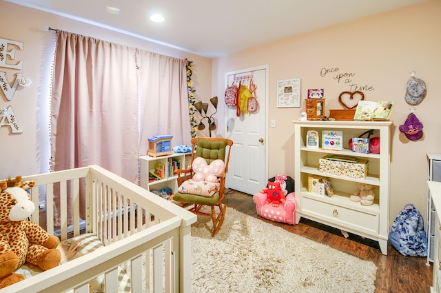 bedroom with dark wood-type flooring and a nursery area