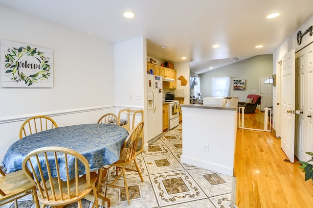 kitchen featuring light brown cabinetry, vaulted ceiling, light hardwood / wood-style flooring, kitchen peninsula, and white appliances