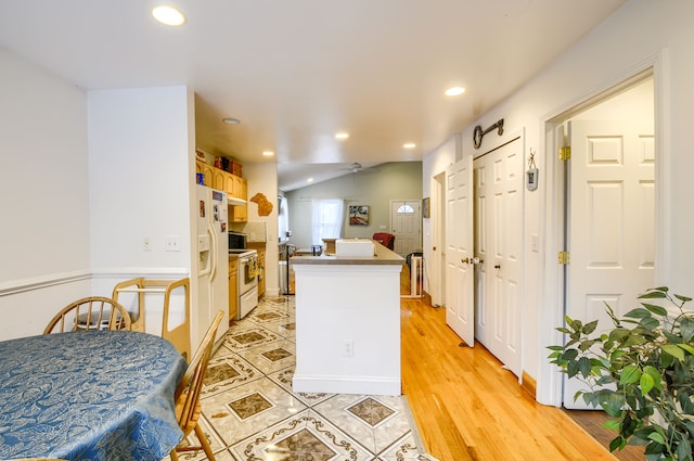 kitchen with light brown cabinetry, light tile patterned floors, white appliances, and vaulted ceiling