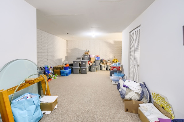 recreation room with carpet floors and brick wall