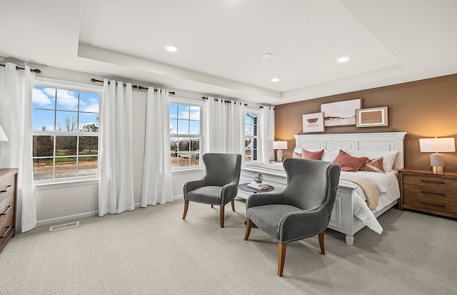 bedroom featuring baseboards, a tray ceiling, visible vents, and light colored carpet